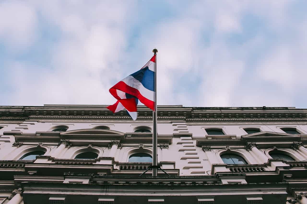 The Thai flag hanging from a building as seen from below.