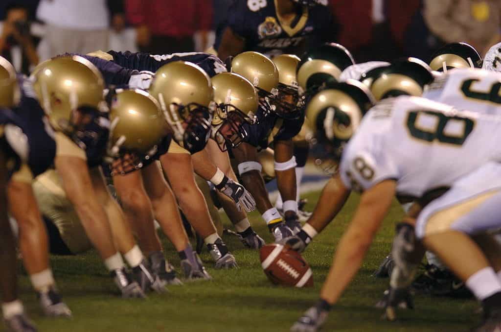 Two American football teams prepare to begin a play. 
