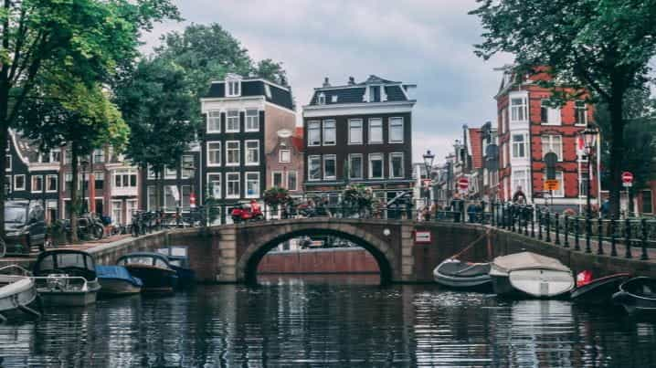 Boats on the river in Amsterdam with a bridge in the background.