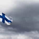 Finnish flag flying on a flagpole with the sky as the background.