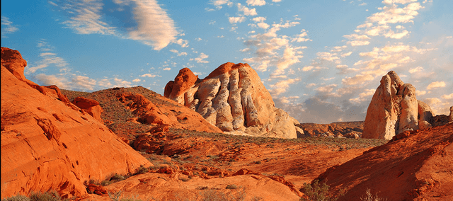 A desert scene with red-orange rocks and dirt, beneath a blue sky.