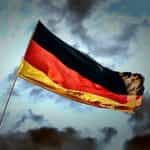 German flag on a flagpole with the sky in the background.