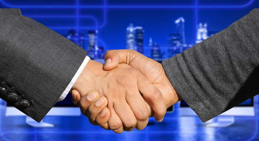 Two hands of businessmen meet in the middle to shake hands.