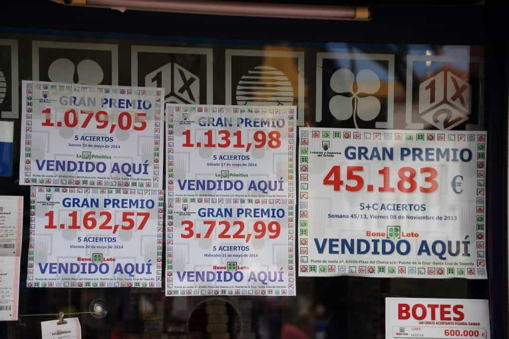 A computer graphic of many different lottery tickets in Spanish in front of a glossy black background. 