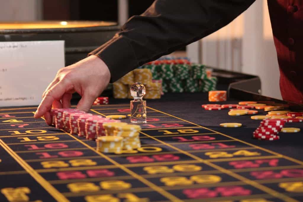 A roulette table with chips on it and a hand placing chips.