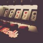 Royal Flush slot machine in a dimly lit casino displays card symbols.