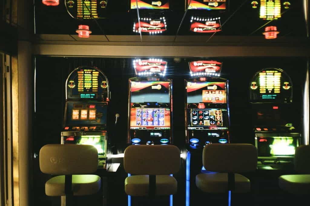 Row of slot machines with chairs in front. 