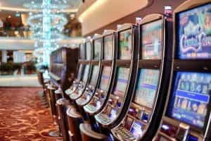 A row of slot machines in a brightly lit lobby. 