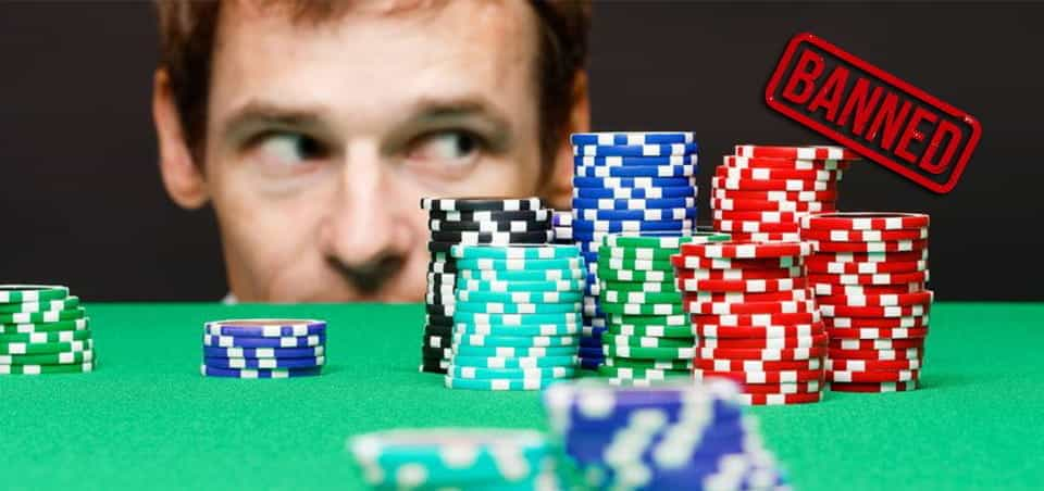 A person looking across the top of a casino table, with casino chips on the table and the word "banned" stamped in the corner.