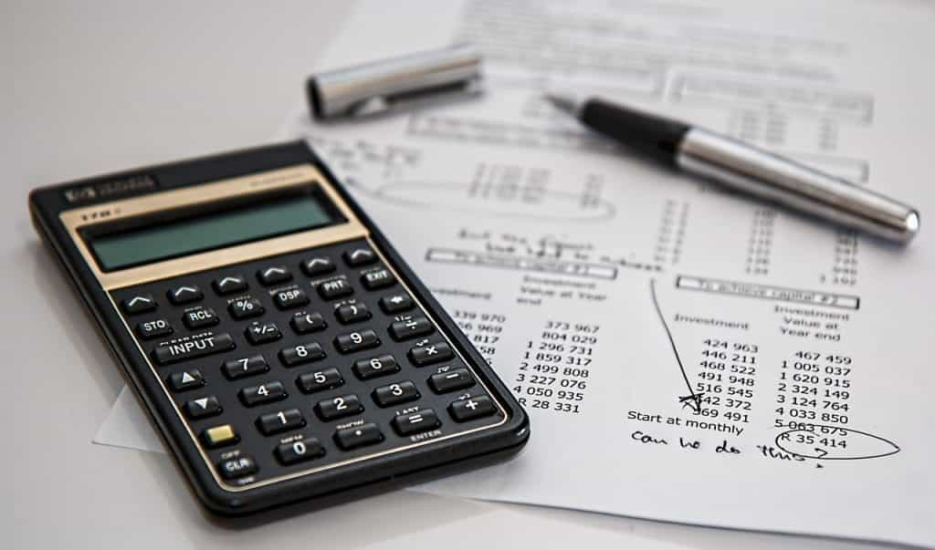 A calculator and a pen on a sheet of paper with account information.