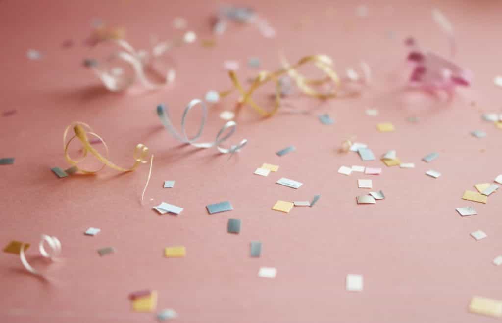 Gold and silver confetti on a pink background. 