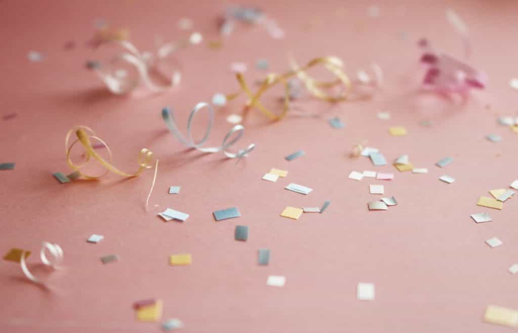 Gold and silver confetti on a pink background.