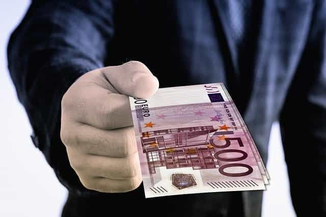 A man handing over Euro banknotes.