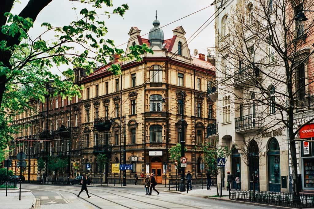 A typical street in Krakow, Poland, with buildings, trees and pedestrians.