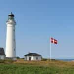 A lighthouse in Denmark with the Danish flag outside.