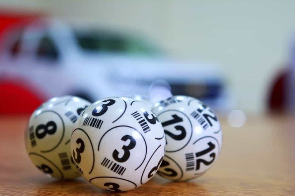 Three white numbered bingo balls sit on a desk. 