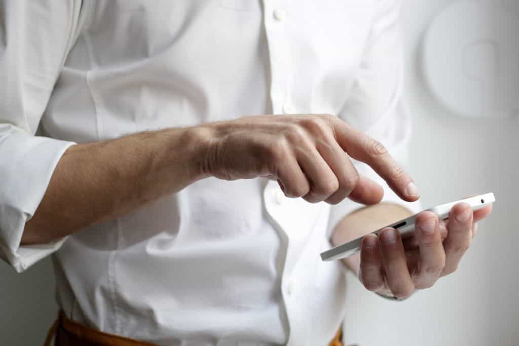 Man in a white shirt using a smartphone.