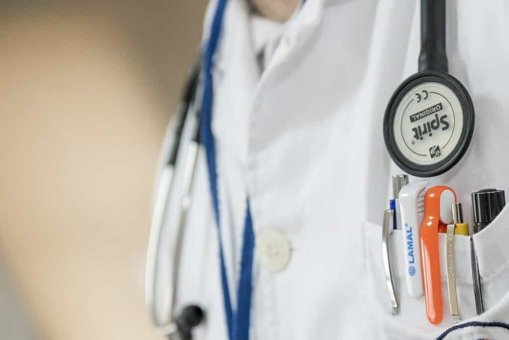 A doctor in white coat with stethoscope and medical equipment.