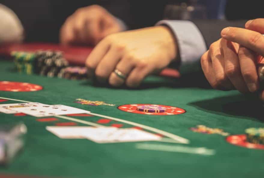 People sat at a casino table with two cards in front of them.