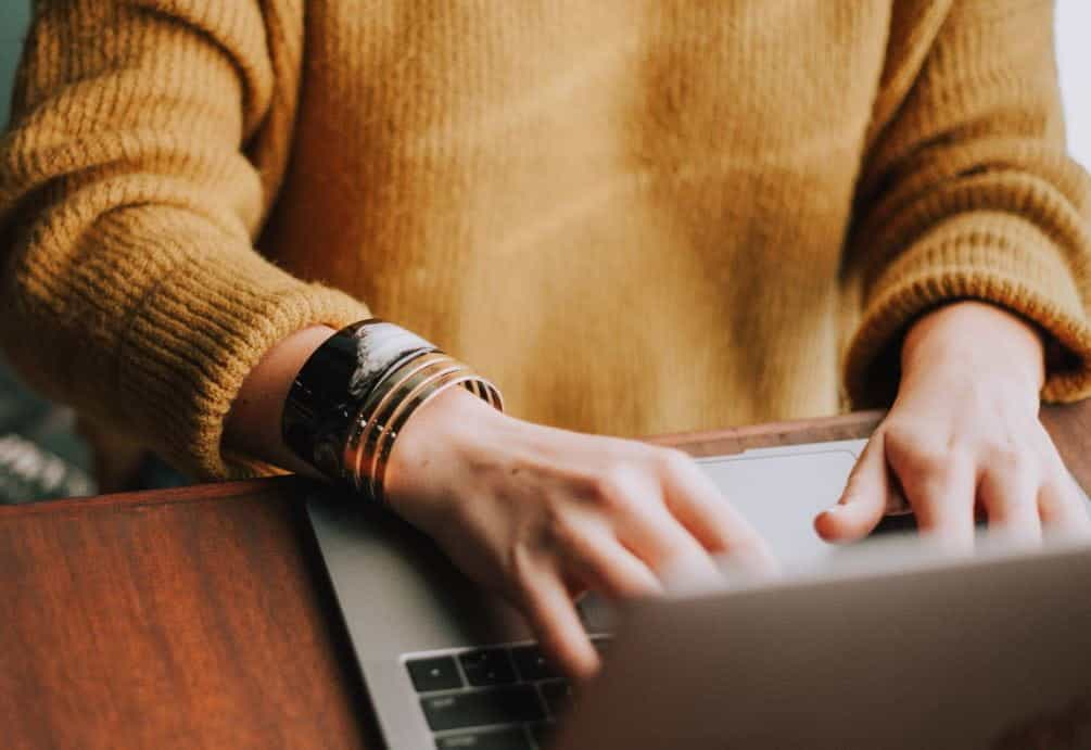 Person sitting at a table, using a laptop. 