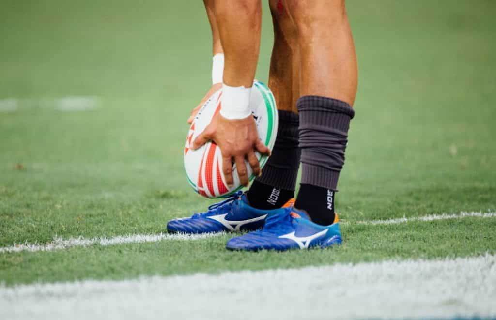 A rugby player prepares to kick the ball. 