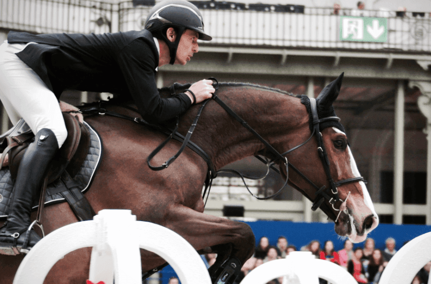 A professional jockey riding a racehorse, in front of a crowd of spectators.