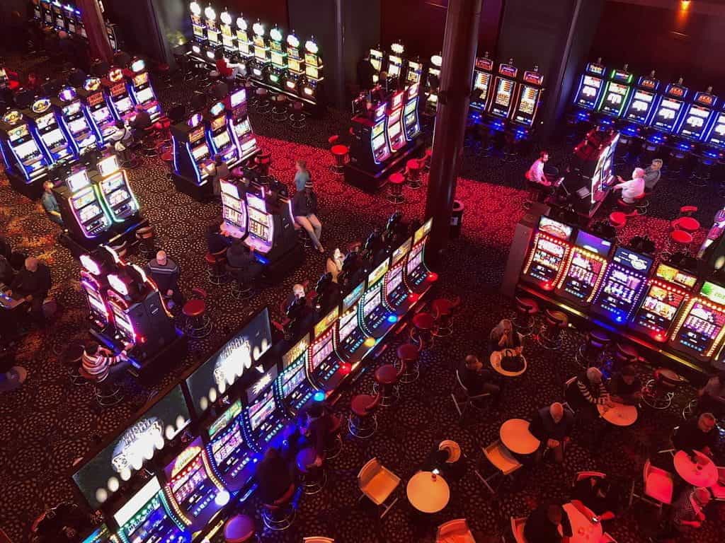 A look down at a dark casino floor, with many glowing slot machines.