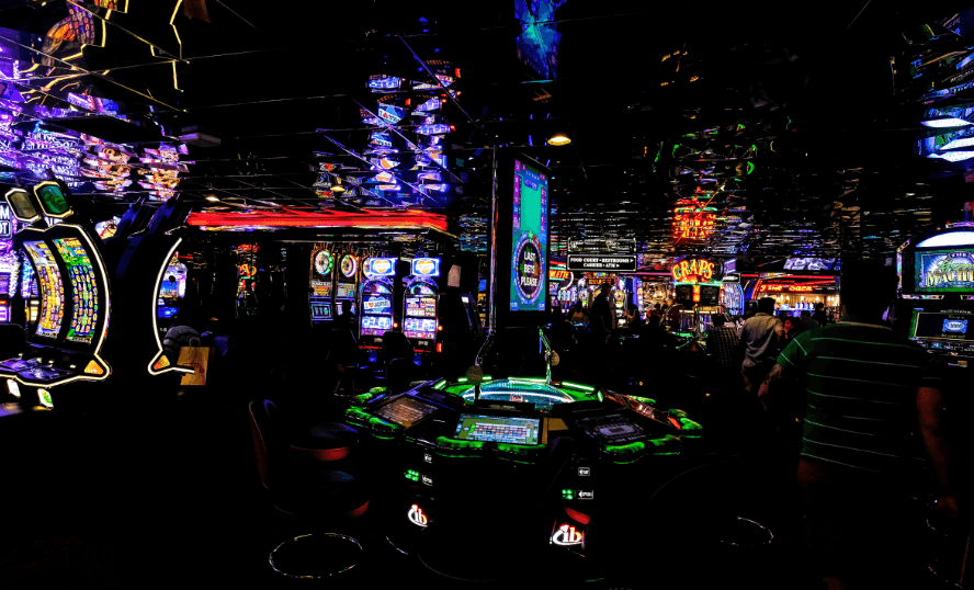 A dark view of a casino, where the neon lights of the machines are reflected off of a mirrored ceiling.