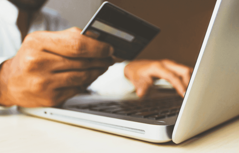 A man working at a laptop holding a credit card.
