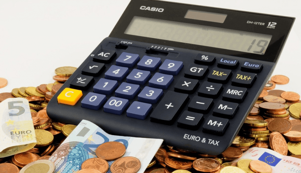 A calculator on top of a pile of euro notes and coins.