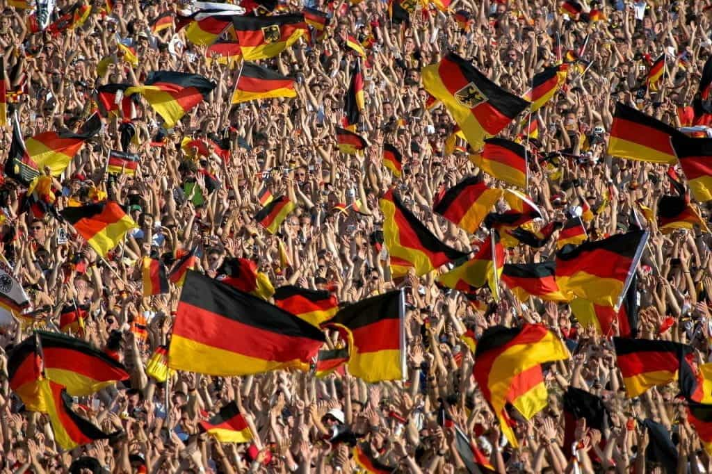 Many German flags being held by supporters at a football game.