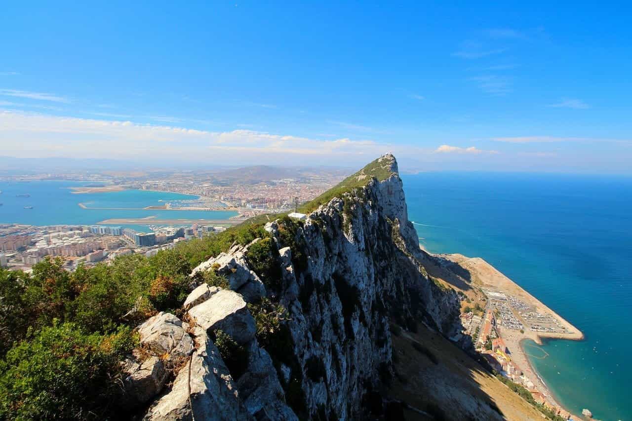 A cliff in Gibraltar with the sea and a city in the background.