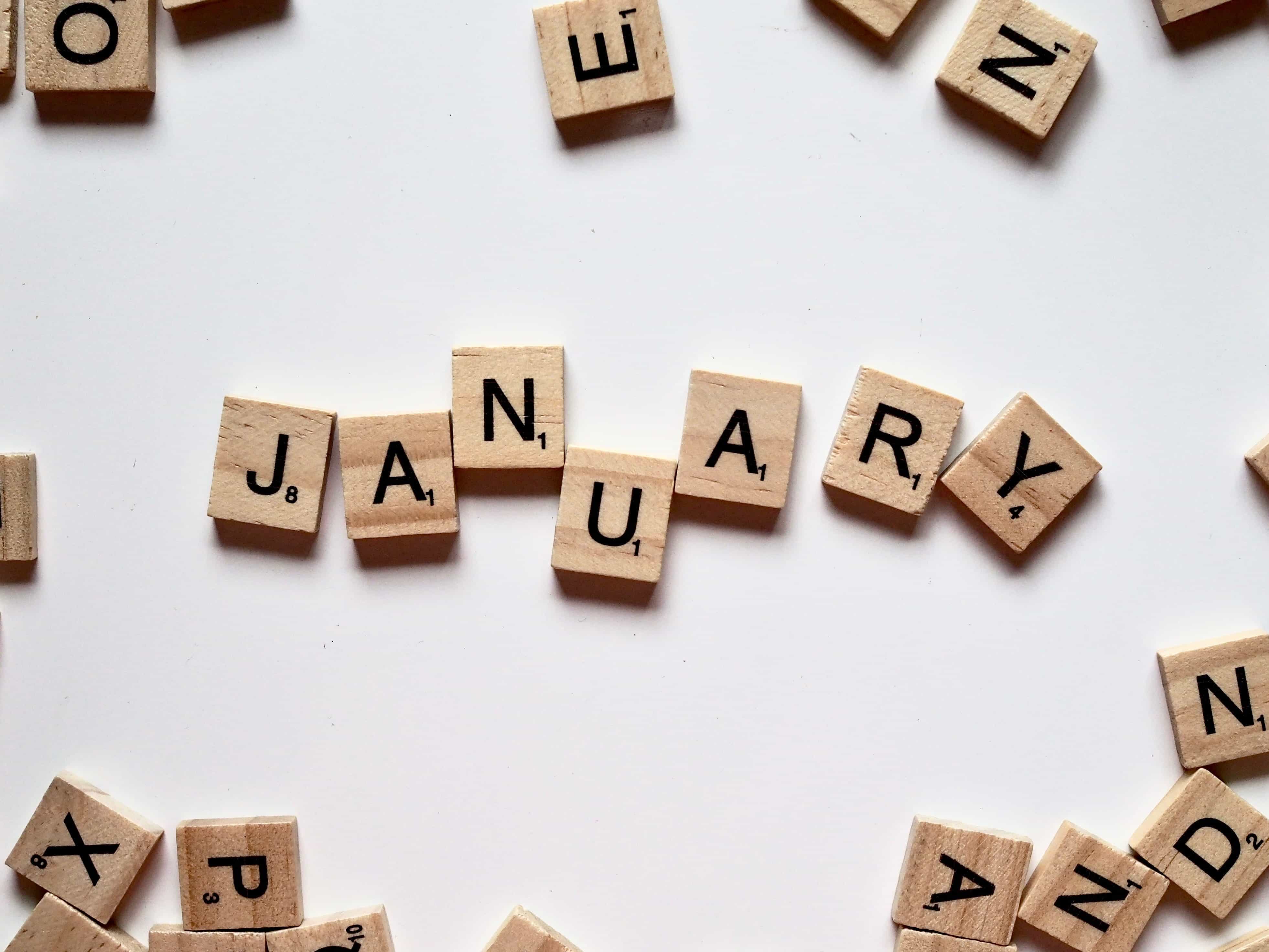 Wooden scrabble letters spell out of January against a white background.