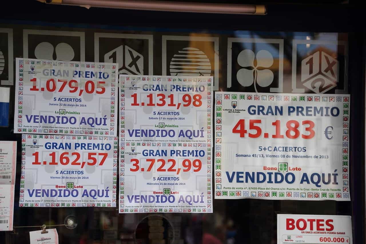 A window display with paper signs advertising lottery jackpots in Spanish.
