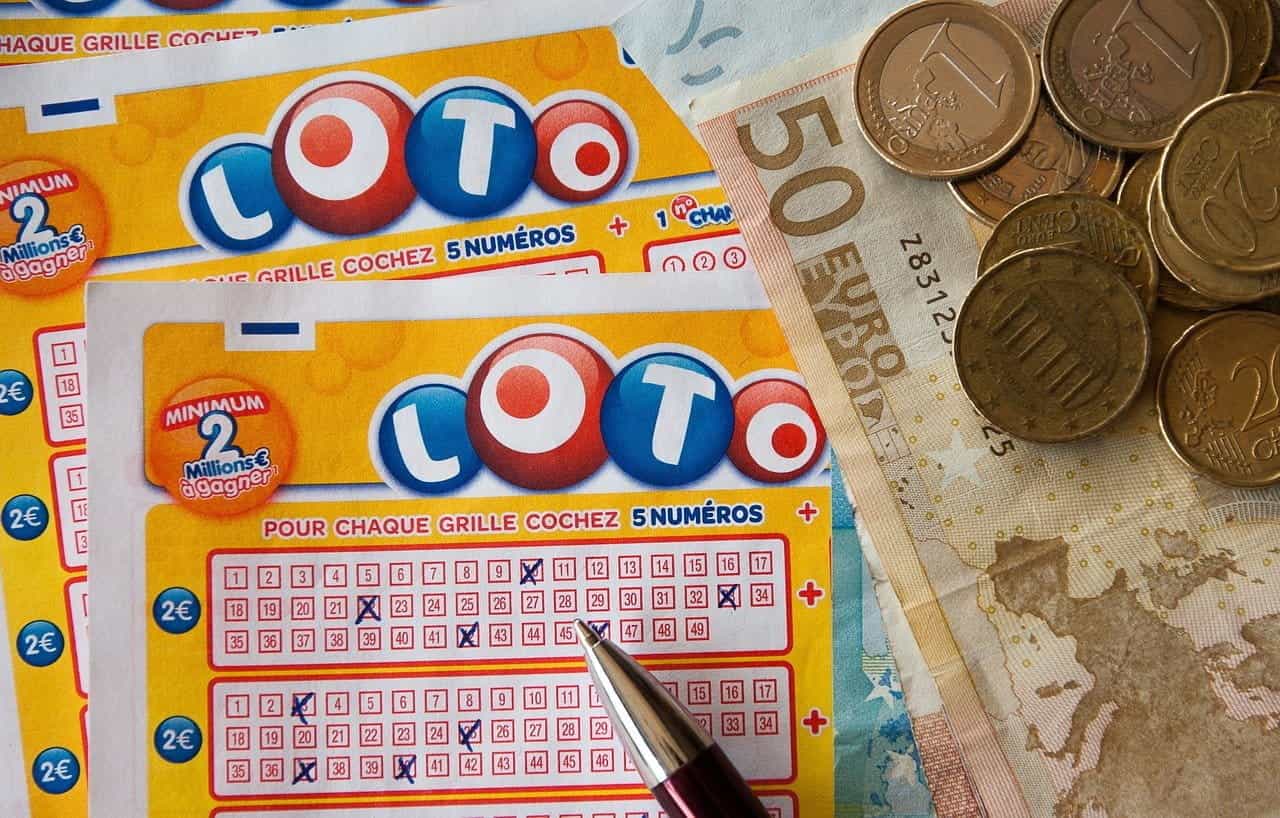 A lottery card with a pen on top and money next to it.