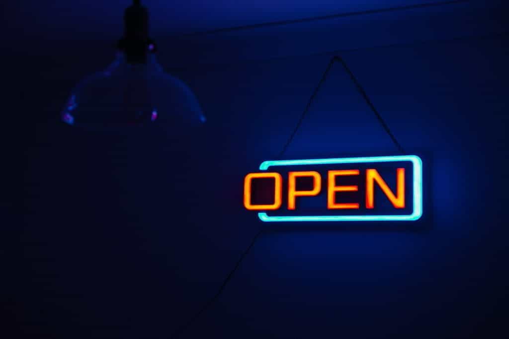 A dark room with a neon open sign lit up in the background.