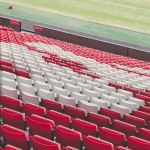 Red plastic seats in an empty football stadium.