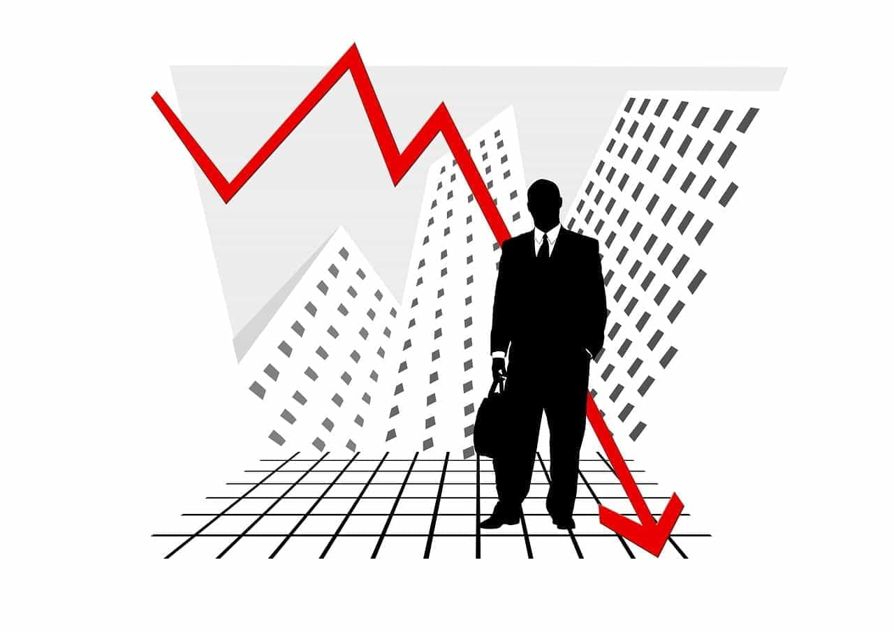 A black and white graphic of a silhouette of a person in a suit standing in front of skyscrapers. A jagged red arrow points down to indicate loss.