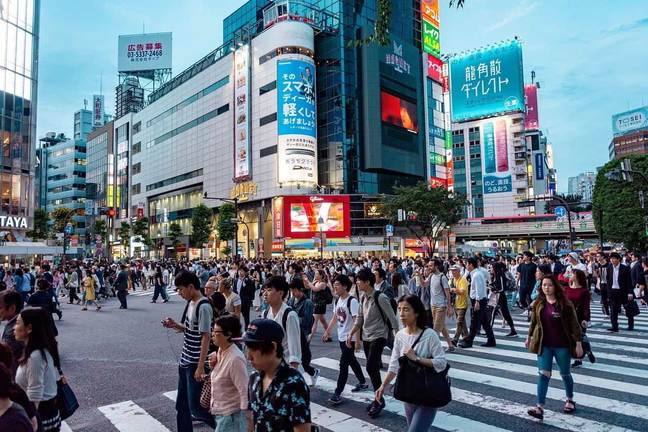 People crossing the road in Tokyo with billboards in the background.
