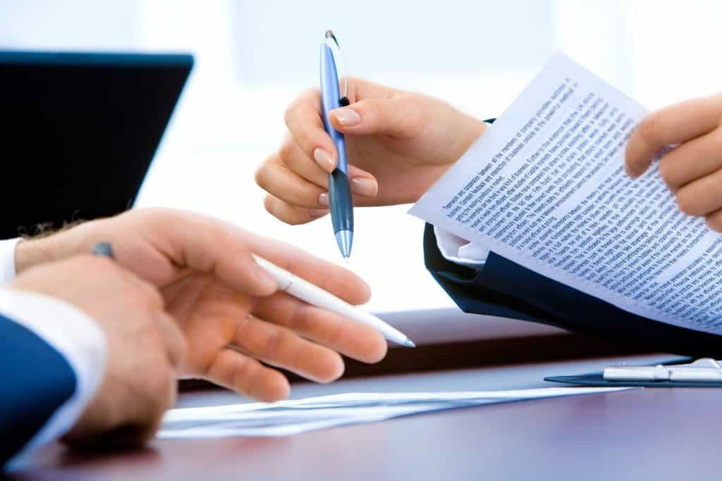 A business deal takes place with pens and documents.