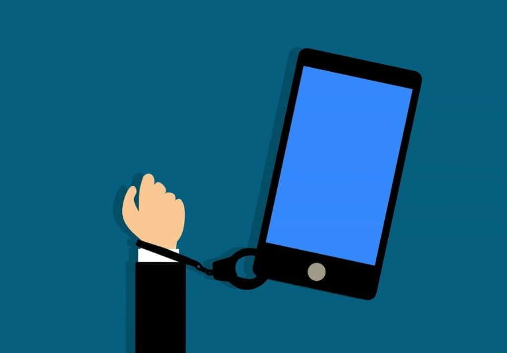 A white hand in a suit jacket handcuffed to a large smartphone.