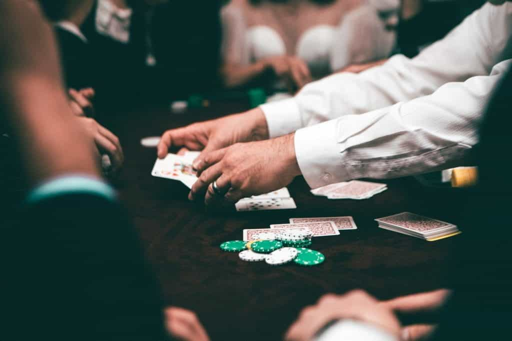 A look at a poker table, where a dealer in a white button-down shirt deals to players.