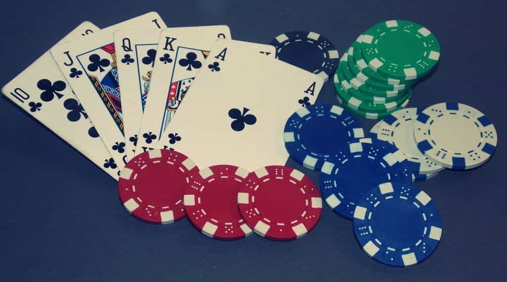 A royal flush poker hand lain on a table beside poker chips.