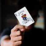 Person holds up a joker playing card in front of their face.