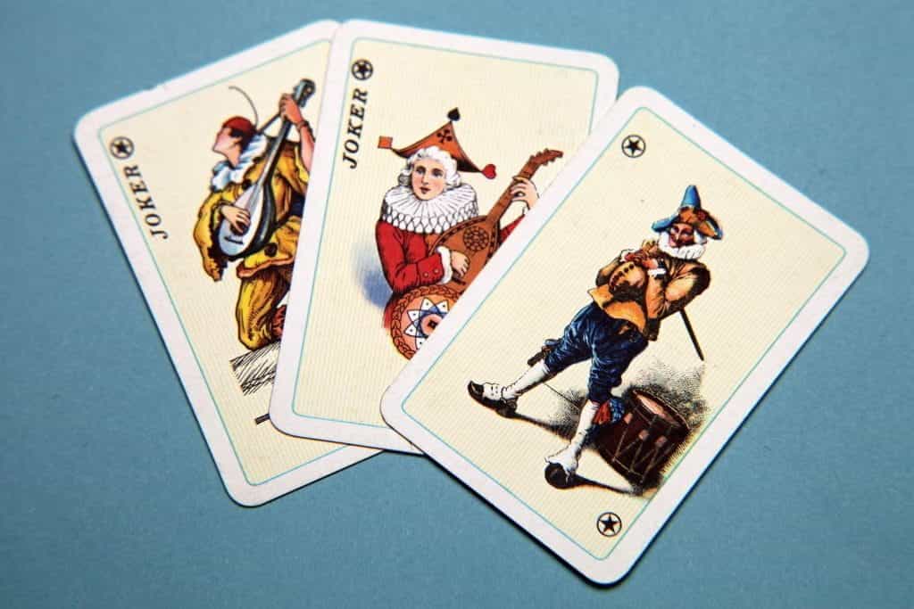 Three joker playing cards splayed out on a light blue backdrop.
