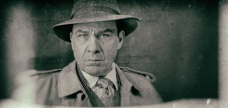 A stereotypical mobster, in trench coat and hat.