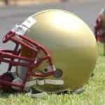A gold American football helmet on the grass.