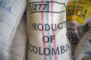 A stack of burlap sacks, with the frontmost labelled PRODUCT OF COLOMBIA.