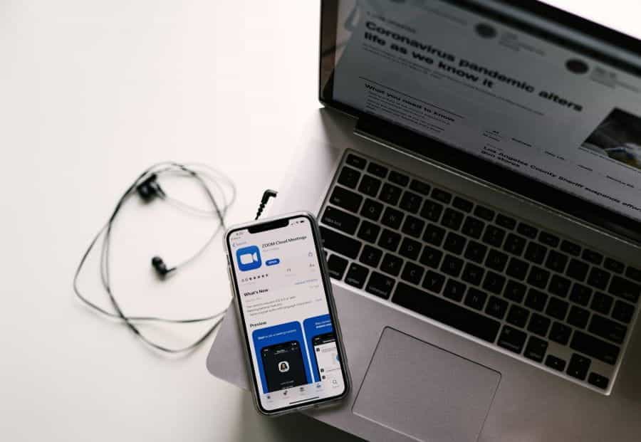 An iPhone rests on a laptop keyboard with the Zoom app open.