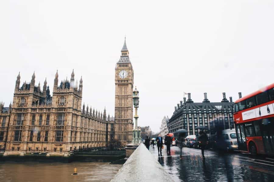 Big Ben and the Houses of Parliament in London, with red bus and pedestrians.